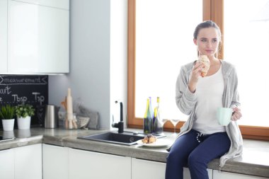 Mutfakta dijital tablet kullanan güzel genç bir kadın..