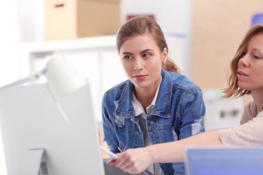 Masanın yanında duran iki genç kadın enstrüman, plan ve dizüstü bilgisayarla.