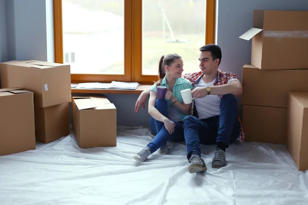 Пара переезжающих в дом сидящих на полу. Пара — стоковое фото