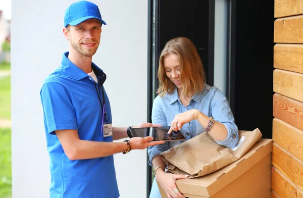 Leende leverans man i blå uniform leverera paket låda till mottagaren - kurir service koncept. Leende leverans man i blå uniform — Stockfoto