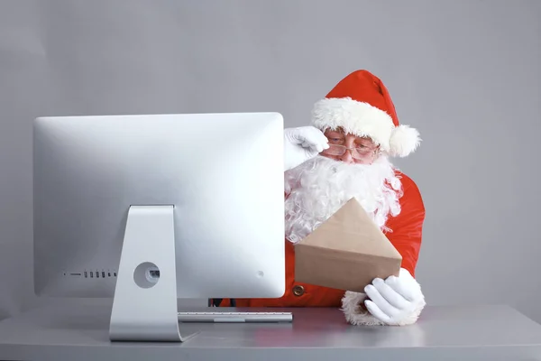 Papai Noel ler cartas de crianças e escrever respostas a eles usando laptop  . — Fotografia de Stock