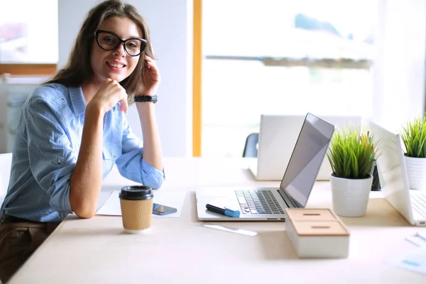 Giovane donna seduta al tavolo dell'ufficio, guardando lo schermo del computer portatile. Giovane donna — Foto Stock