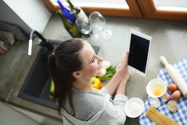 Schöne Frau beim Kuchenbacken in Küche neben Schreibtisch. — Stockfoto