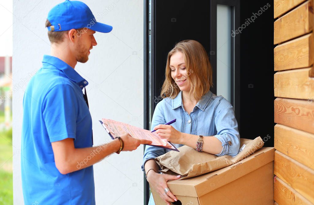 Smiling delivery man in blue uniform delivering parcel box to recipient - courier service concept. Smiling delivery man in blue uniform