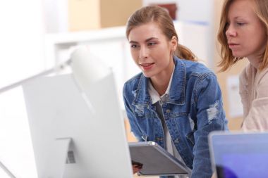 Masanın yanında duran iki genç kadın enstrüman, plan ve dizüstü bilgisayarla.