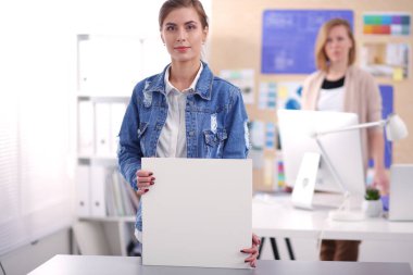 Masanın yanında duran iki genç kadın enstrüman, plan ve dizüstü bilgisayarla.