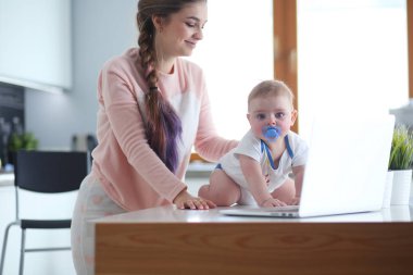 Annesi bebeğini evde parlak mutfakta ile.