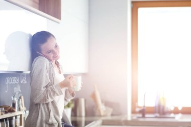 modern mutfakta otururken cep telefonu kullanan kadın.