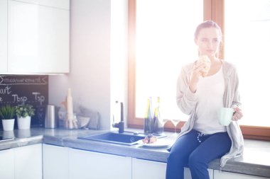 Mutfakta dijital tablet kullanan güzel genç bir kadın..