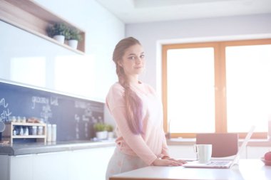 Cep telefonu ayakta modern mutfak kullanan kadın.