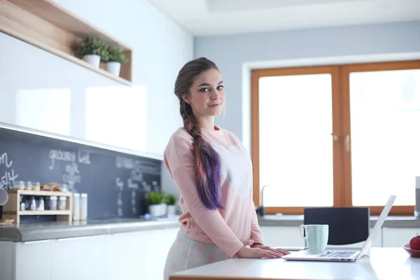 Femme utilisant un téléphone portable debout dans la cuisine moderne . — Photo