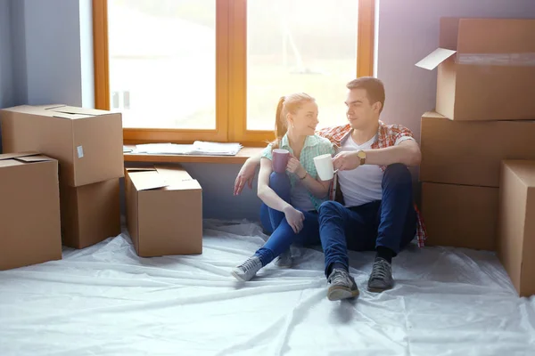 Couple moving in house sitting on the floor. Couple