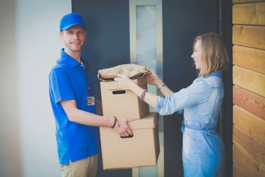 Mavi üniformalı gülümseyen kurye servis konseptine paket kutusu teslim eden teslimatçı. Mavi üniformalı gülümseyen teslimatçı.
