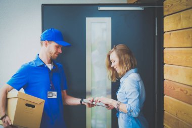Mavi üniformalı gülümseyen kurye servis konseptine paket kutusu teslim eden teslimatçı. Mavi üniformalı gülümseyen teslimatçı.