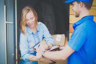 Mavi üniformalı gülümseyen kurye servis konseptine paket kutusu teslim eden teslimatçı. Mavi üniformalı gülümseyen teslimatçı.