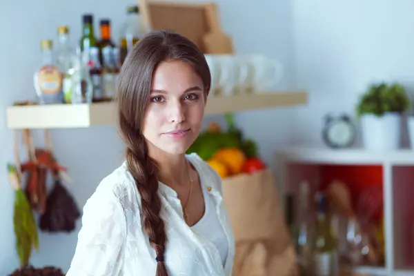 Mujer joven de pie cerca de escritorio en la cocina. Mujer joven . — Foto de Stock