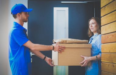 Mavi üniformalı gülümseyen kurye servis konseptine paket kutusu teslim eden teslimatçı. Mavi üniformalı gülümseyen teslimatçı.