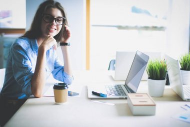 Ofis masasında oturan genç bir kadın dizüstü bilgisayar ekranına bakıyor. Genç kadın.