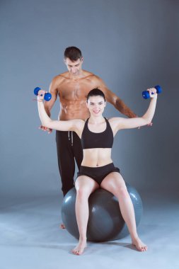 Spor salonunda fitness topu iki gülümseyen insanlarla. Kişisel fitness eğitmeni. Kişisel eğitim. Jimnastik salonu iş.