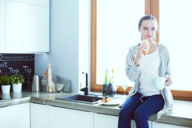 Mutfakta dijital tablet kullanan güzel genç bir kadın..