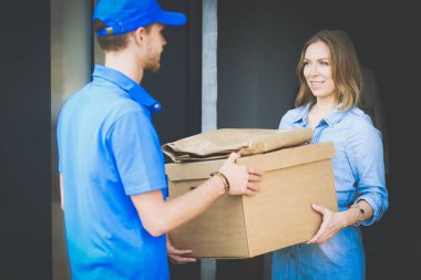 Mavi üniformalı gülümseyen kurye servis konseptine paket kutusu teslim eden teslimatçı. Mavi üniformalı gülümseyen teslimatçı.