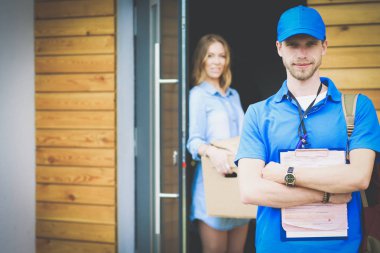 Mavi üniformalı gülümseyen kurye servis konseptine paket kutusu teslim eden teslimatçı. Mavi üniformalı gülümseyen teslimatçı.