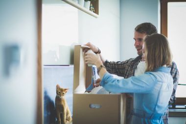 Genç bir çift yeni evde büyük karton kutu taşıyan. Ev taşıma. Genç Çift