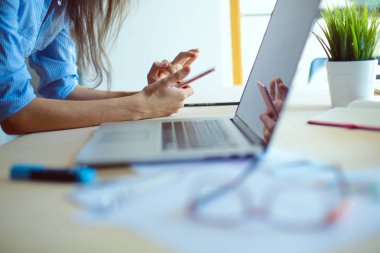 Ofis masasında oturan ve cep telefonuyla konuşan genç ve güzel bir iş kadını. İş kadını