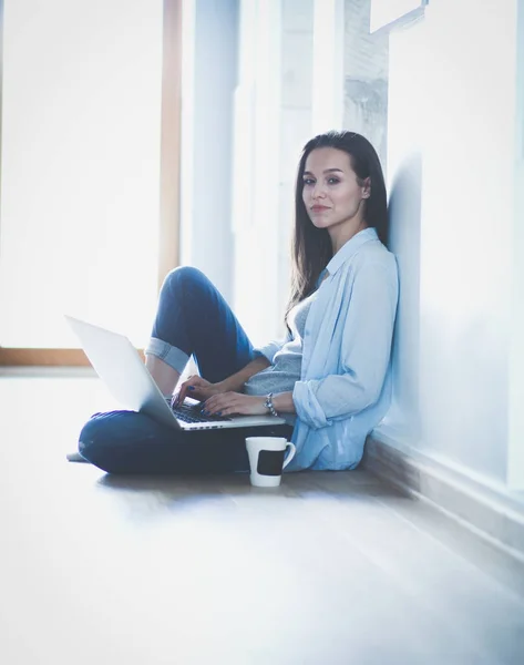 Young beautiful woman at home sitting on the floor with laptop. Young beautiful woman.