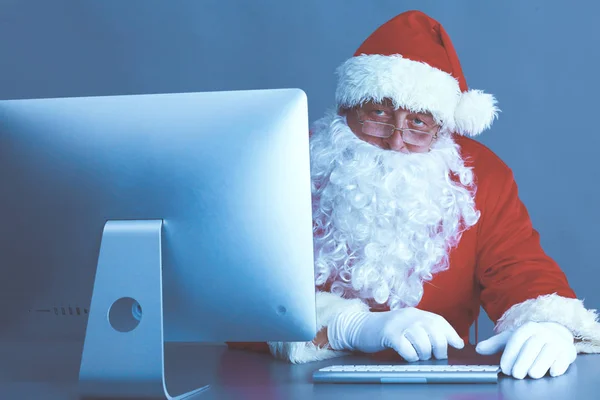 Papai Noel ler cartas de crianças e escrever respostas a eles usando laptop  . — Fotografia de Stock