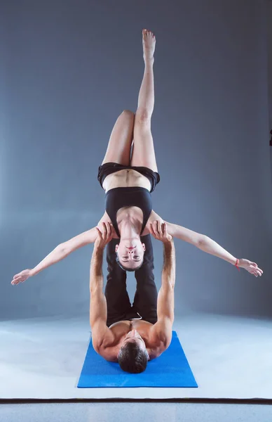 Young couple practicing acro yoga on mat in studio together. Acroyoga. Couple yoga. Partner yoga.