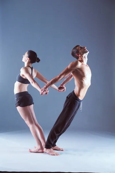 Casal jovem praticando acro ioga no tapete em estúdio juntos. Acroyoga. Um par de ioga. Parceiro ioga . — Fotografia de Stock