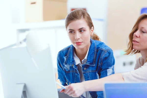 Two young woman standing near desk with instruments, plan and laptop. — Stock Photo, Image