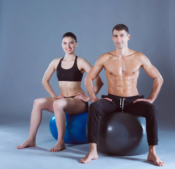 Two smiling people with fitness ball in the gym. Personal fitness instructor. Personal training. Gym workout.