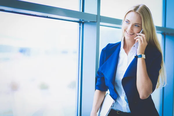 Femme d'affaires debout contre la fenêtre du bureau parlant sur le téléphone mobile. Femme d'affaires — Photo