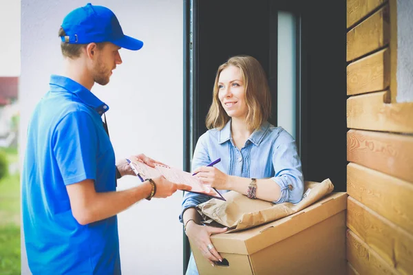 Homem de entrega sorridente em uniforme azul entregando caixa de encomendas ao destinatário conceito de serviço de correio. Sorrindo homem de entrega em uniforme azul — Fotografia de Stock