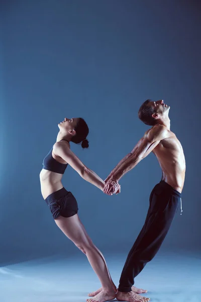 Young couple practicing acro yoga on mat in studio together. Acroyoga. Couple yoga. Partner yoga.