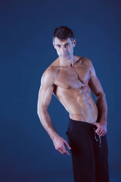 Homem musculado. Homem musculoso sobre um fundo cinzento mostrando músculos. Instrutor de fitness. Profissional de fitness. Treino. Aptidão dos homens . — Fotografia de Stock