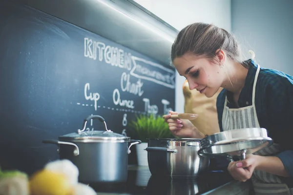 Молодая женщина, стоящая у плиты на кухне . — стоковое фото