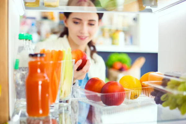 Портрет женщины, стоящей рядом с открытым холодильником, полным здоровой пищи, овощей и фруктов. Портрет женщины — стоковое фото