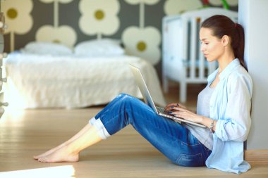 Çocuk karyolası dizüstü bilgisayar ile yakın katta oturan bir genç bayan. Genç anne