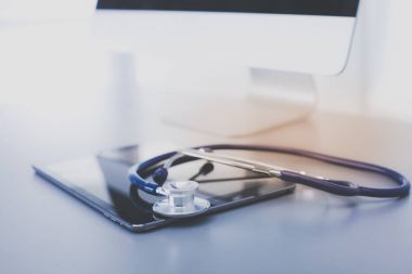 Tıbbi ekipman: Beyaz arka planda mavi steteskop ve tablet. Tıbbi ekipman