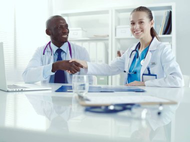 Ofiste tokalaşırken gülümseyen iki genç tıp adamı. Doktorlar. Takım çalışması.