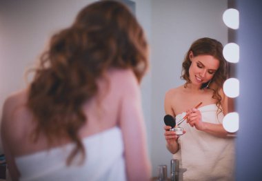Telefon ile banyo üzerinde duran genç kadın.