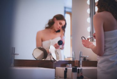 Telefon ile banyo üzerinde duran genç kadın.