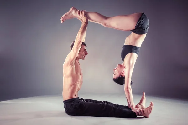 Pareja joven practicando acro yoga en estera en estudio juntos. Acroyoga. Un par de yoga. Socio yoga . —  Fotos de Stock