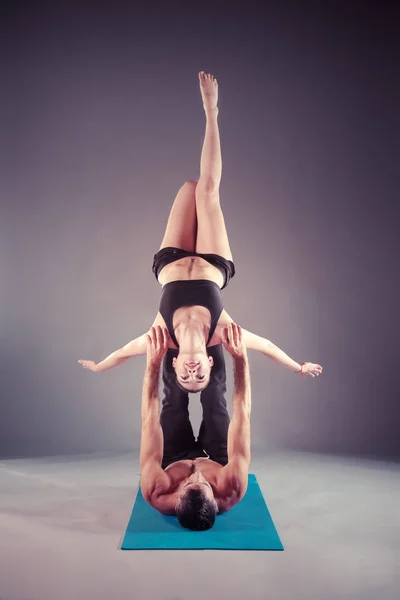 Young couple practicing acro yoga on mat in studio together. Acroyoga. Couple yoga. Partner yoga.