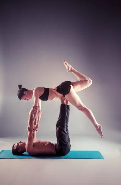 Pareja joven practicando acro yoga en estera en estudio juntos. Acroyoga. Un par de yoga. Socio yoga . — Foto de Stock