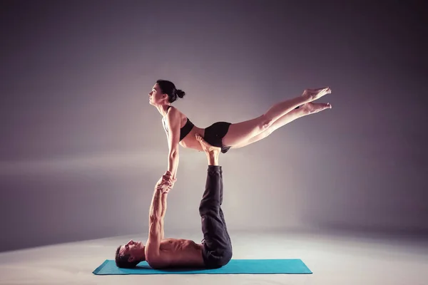 Jong koppel acro yoga beoefenen op mat samen in de studio. Acroyoga. Paar yoga. Partner yoga. — Stockfoto