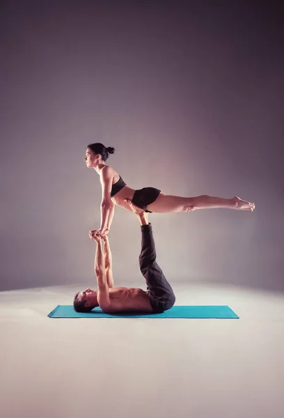 Jong koppel acro yoga beoefenen op mat samen in de studio. Acroyoga. Paar yoga. Partner yoga. — Stockfoto